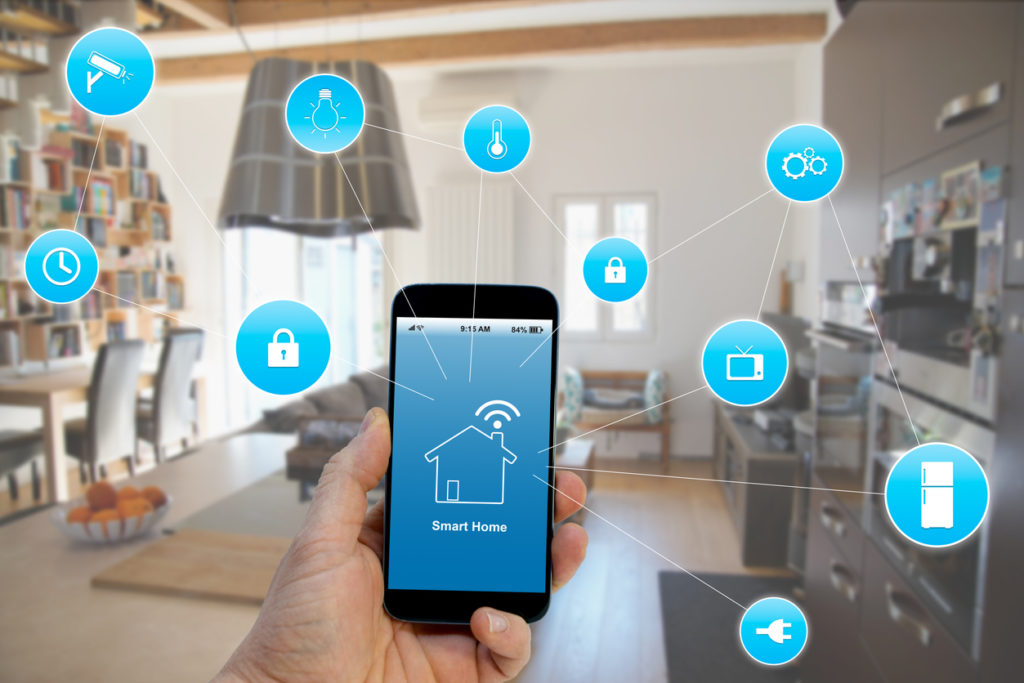 Hand holding smartphone with smart home application on screen.