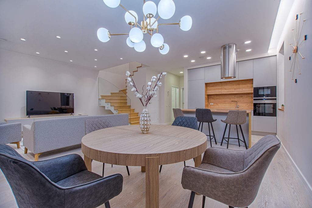 Modern living room with recessed lighting throughout and decorative light fixture over dining table.
